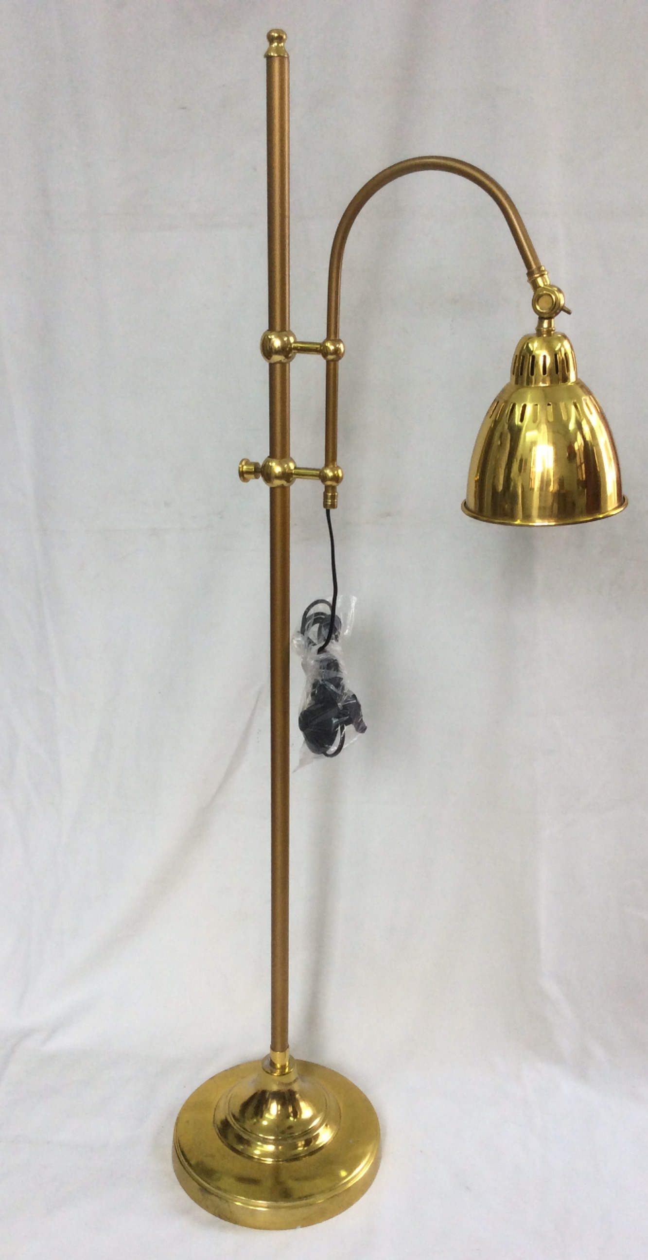Decorative table lamp with a brass base and intricate floral patterns, illuminated with a warm light, placed on a wooden surface in a cozy indoor setting